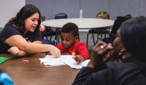 photo of a social worker at a table with a young boy