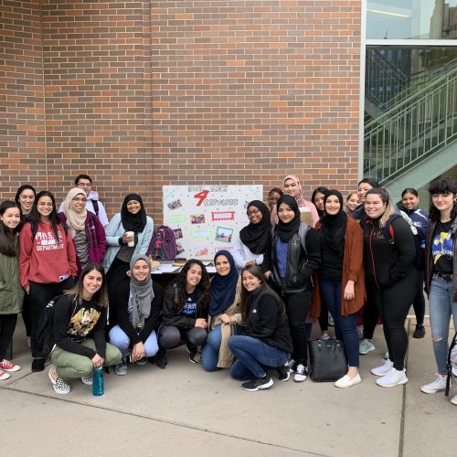 Students from the Muslim Students Association and Dr. Gerlach's HS-123 course surround a table advertising they're collecting donations outside the McMahon Student Center in April.