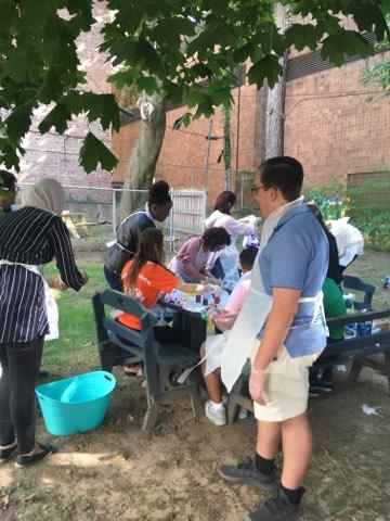 One student dampens her shirt in a bucket before beginning to dye while another student looks on.