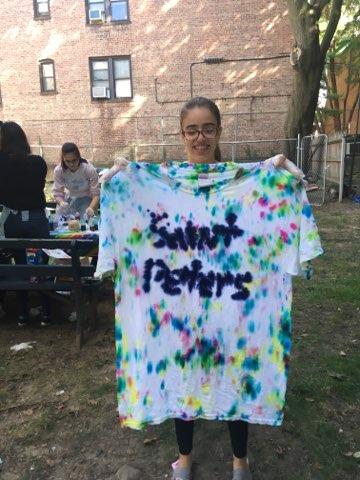 Sophomore Leslien Ruiz holds up her completed shirt with a colorful pattern and "Saint Peter's" written in the middle.