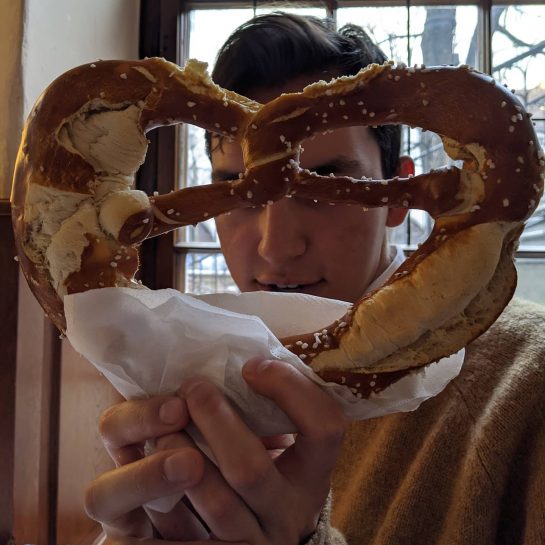 Student Hunter Criollo holds a large pretzel, which is shaped like a heart, in front of his face at a cafe in Bavaria.
